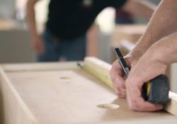 A pair of hands measuring a piece of wood.