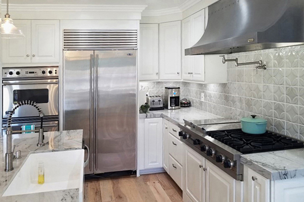 Corner of kitchen with white cabinets, high-end stainless steel appliances and white apron sink in island Corner of kitchen with white cabinets, high-end stainless steel appliances and white apron sink in island