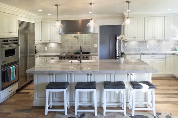 Large kitchen with white cabinets, island with seating, wood floors and professional stainless steel appliances Large kitchen with white cabinets, island with seating, wood floors and professional stainless steel appliances