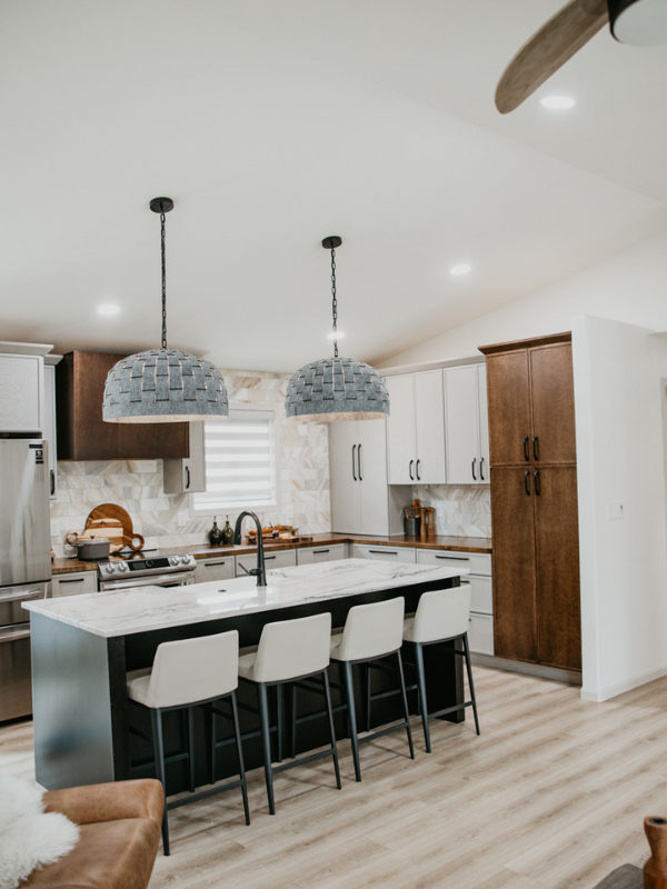 Tri-tone kitchen design with skinny shaker cabinets in light gray and medium brown with a black island and white stone countertops