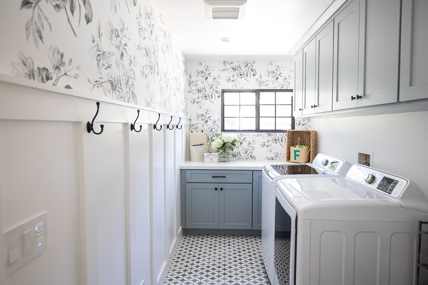 Laundry room cabinets painted a calming shade of blue with floral wallpaper and board and batten trim on the wall. Laundry room cabinets painted a calming shade of blue with floral wallpaper and board and batten trim on the wall.