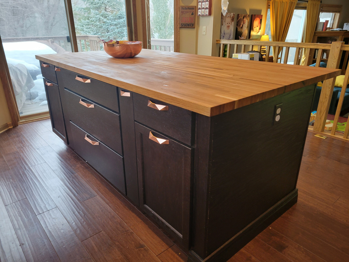 Black shaker island cabinets with baseboard molding and geometric brushed nickel hardware 
