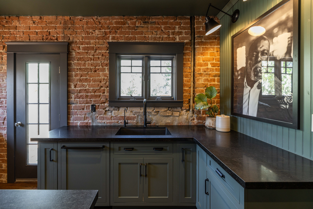 U-shaped large green kitchen with inset cabinets, vintage elements and dark brown island with black granite countertops and hardware U-shaped large green kitchen with inset cabinets, vintage elements and dark brown island with black granite countertops and hardware