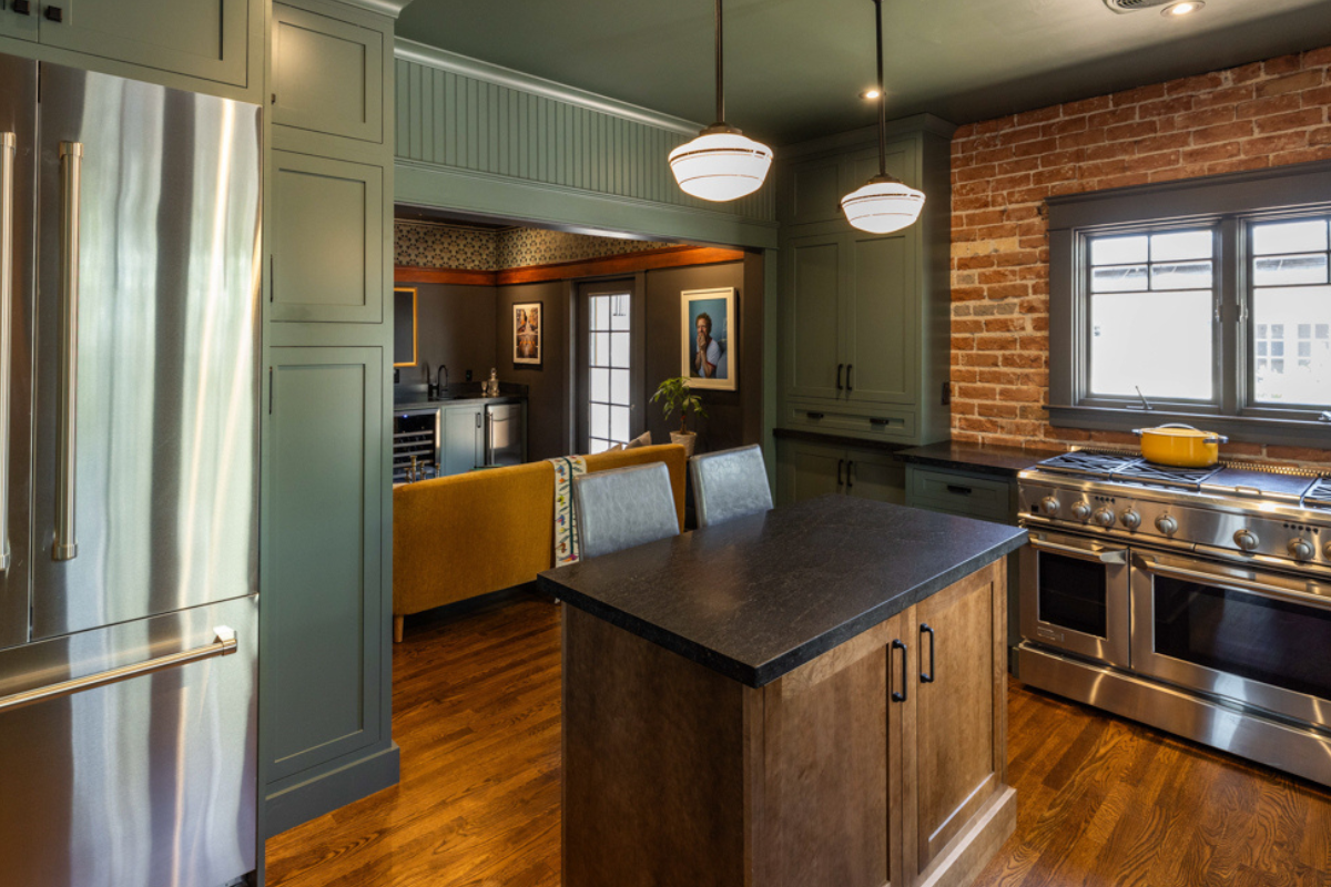 U-shaped large green kitchen with inset cabinets, vintage elements and dark brown island with black granite countertops and hardware U-shaped large green kitchen with inset cabinets, vintage elements and dark brown island with black granite countertops and hardware