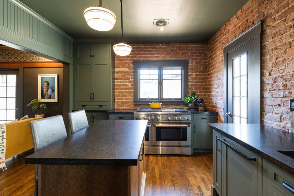 U-shaped large green kitchen with inset cabinets, vintage elements and dark brown island with black granite countertops and hardware U-shaped large green kitchen with inset cabinets, vintage elements and dark brown island with black granite countertops and hardware