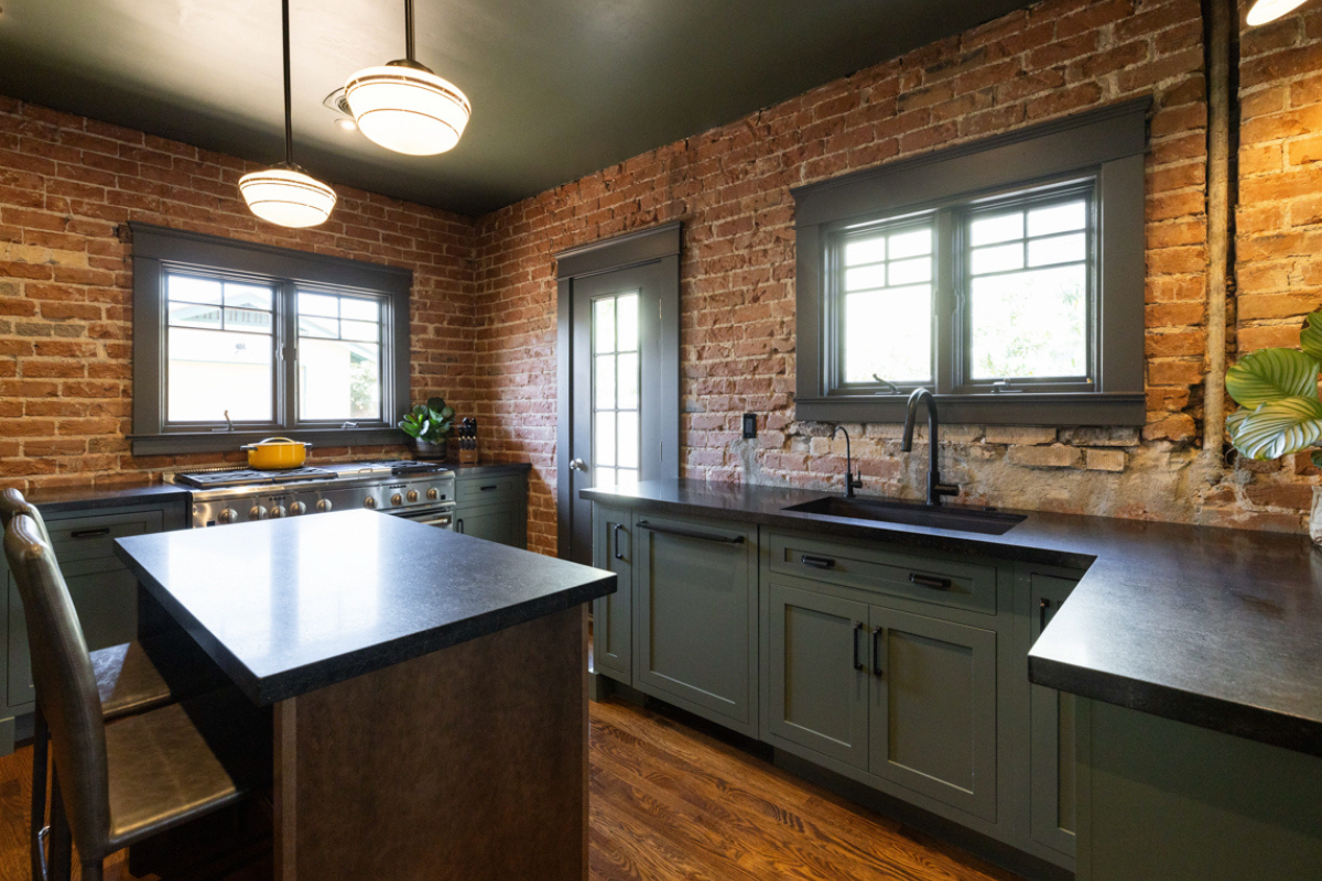 U-shaped large green kitchen with inset cabinets, vintage elements and dark brown island with black granite countertops and hardware U-shaped large green kitchen with inset cabinets, vintage elements and dark brown island with black granite countertops and hardware