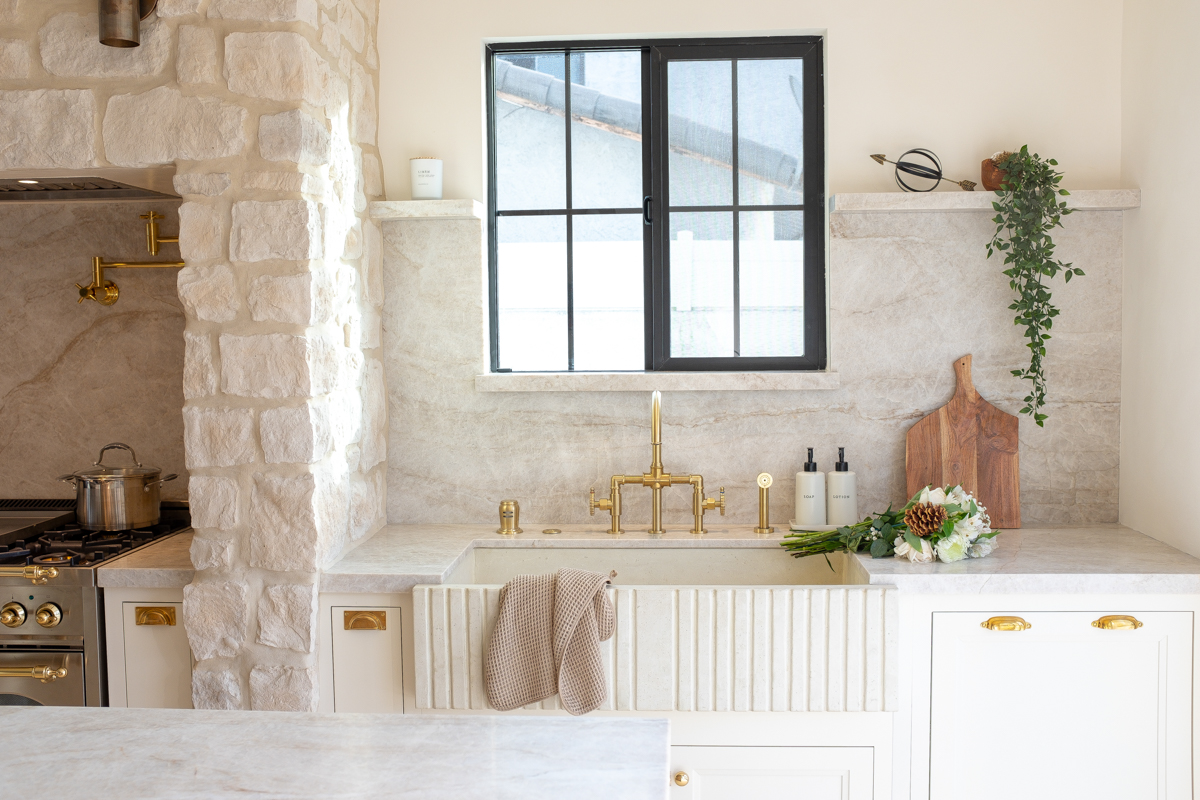 White inset base cabinets with a white fluted farmhouse sink and black-framed window above White inset base cabinets with a white fluted farmhouse sink and black-framed window above