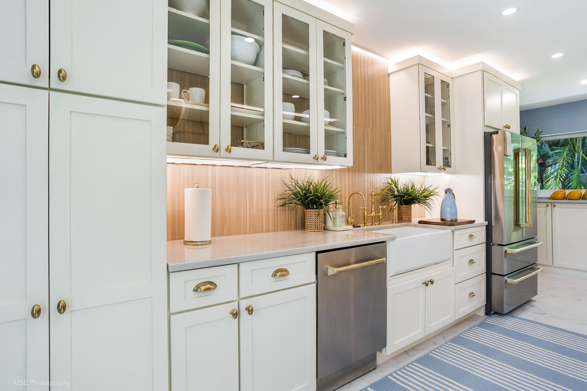 Soft white shaker kitchen cabinets with brass hardware and a modern wood slat backsplash Soft white shaker kitchen cabinets with brass hardware and a modern wood slat backsplash