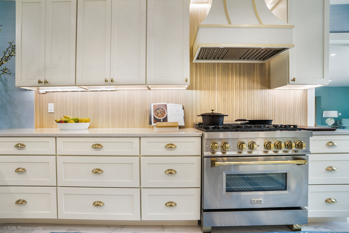 Soft white shaker kitchen cabinets with brass hardware and a modern wood slat backsplash Soft white shaker kitchen cabinets with brass hardware and a modern wood slat backsplash