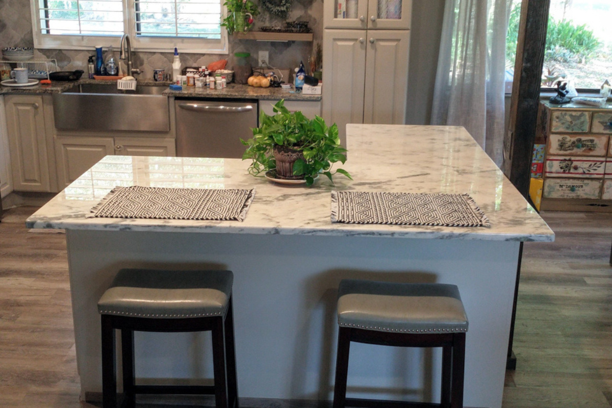 L-shaped kitchen design with L-shaped island in cream colored raised panel kitchen cabinets