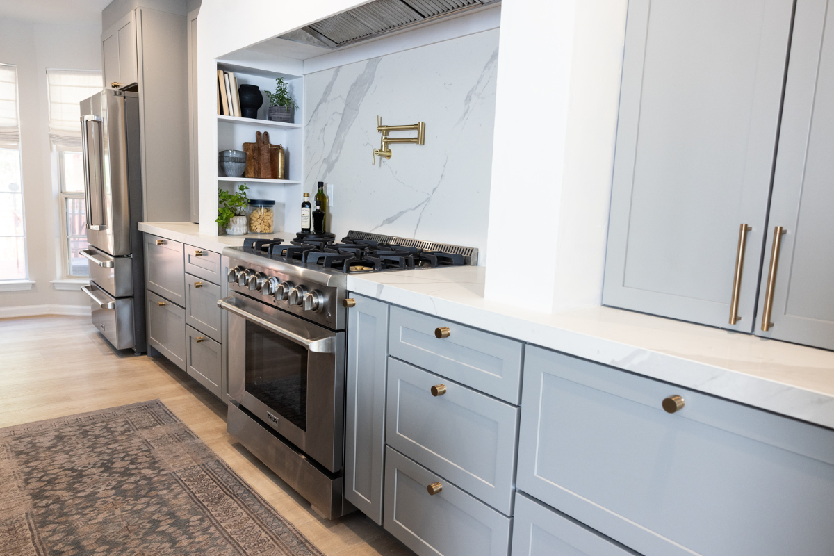 One-wall kitchen design with light gray shaker cabinets, a large white custom curved hood and white quartz countertops and backsplash One-wall kitchen design with light gray shaker cabinets, a large white custom curved hood and white quartz countertops and backsplash