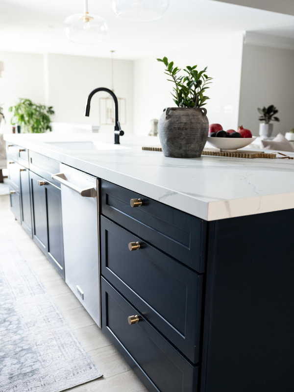 Dark blue shaker kitchen island with white quartz countertops and gold cabinet hardware Dark blue shaker kitchen island with white quartz countertops and gold cabinet hardware