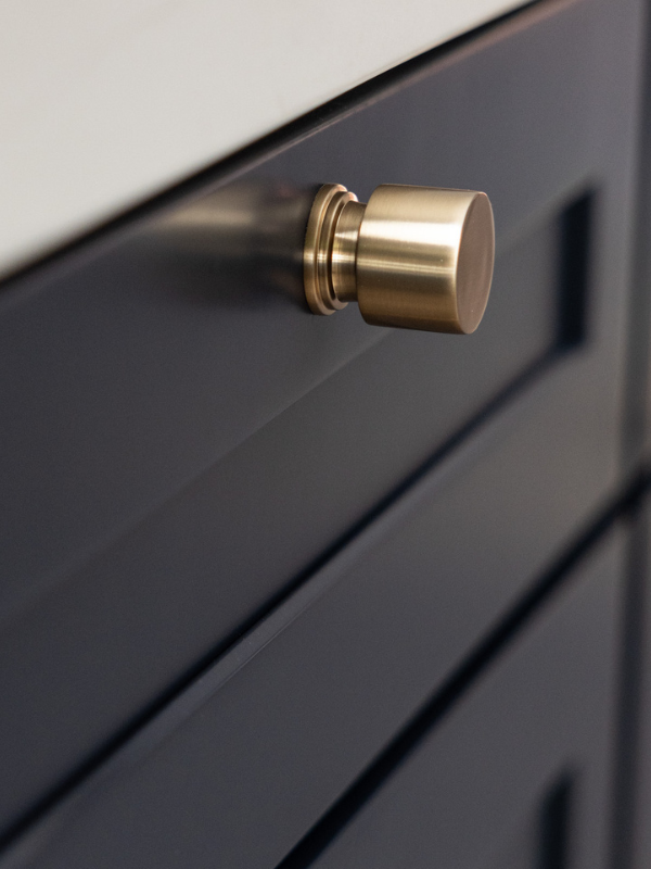 Close-up of dark blue shaker base cabinets with round golden knobs Close-up of dark blue shaker base cabinets with round golden knobs