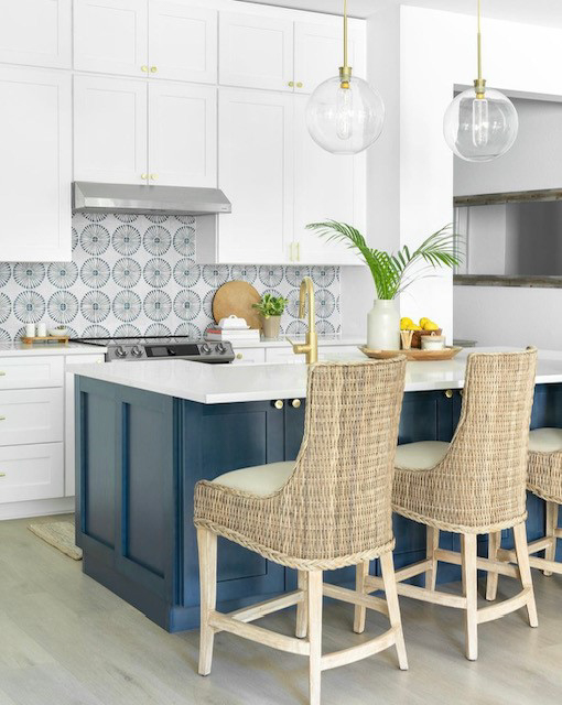 Stacked white shaker kitchen cabinets with gold cabinet hardware and a navy blue island with white quartz countertops 