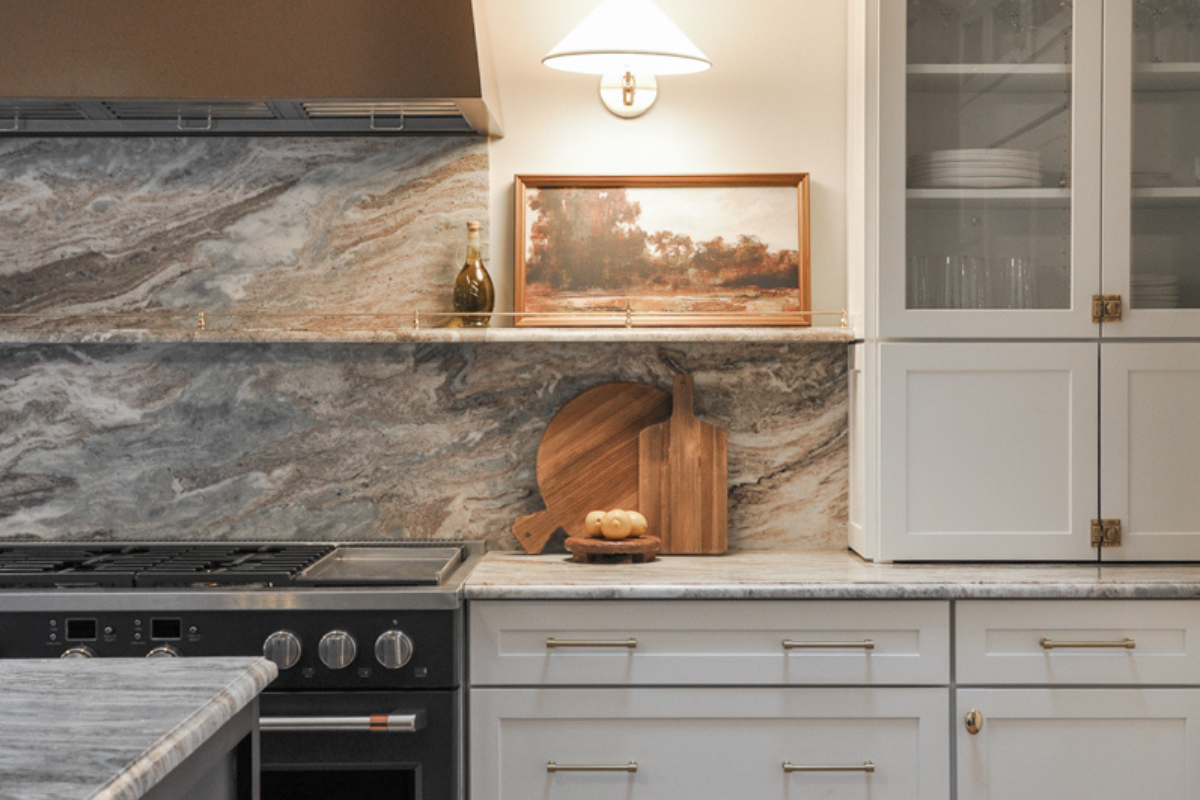 White shaker kitchen cabinets with stacked furniture wall cabinets, brass hardware, and a black chef's range White shaker kitchen cabinets with stacked furniture wall cabinets, brass hardware, and a black chef's range