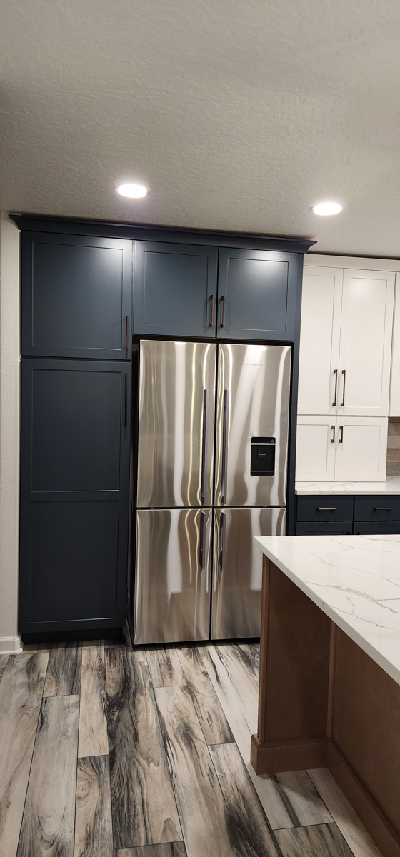 Farmhouse kitchen with white shaker wall cabinets, blue shaker base cabinets, and light wood furniture-style island Farmhouse kitchen with white shaker wall cabinets, blue shaker base cabinets, and light wood furniture-style island