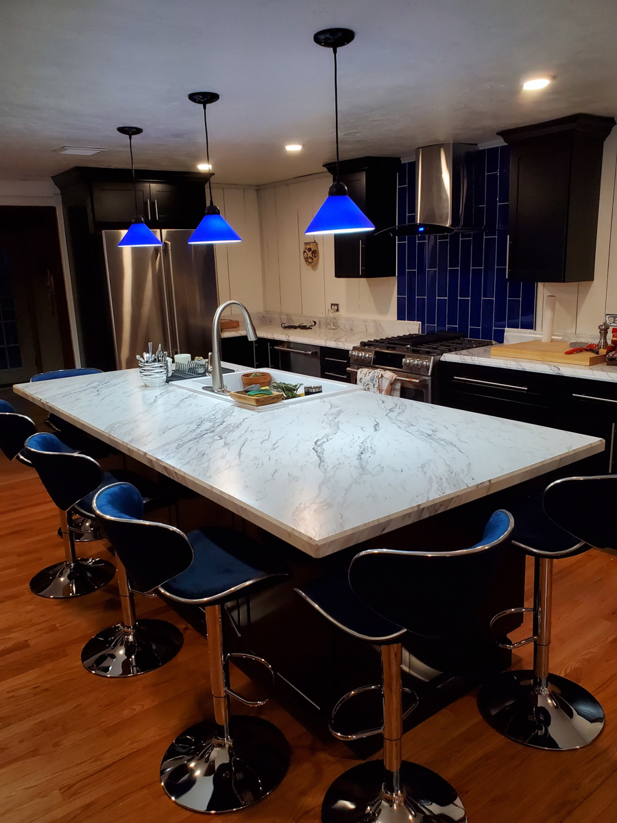 Black shaker kitchen cabinets with white countertops, blue lighting, and blue subway tile backsplash Black shaker kitchen cabinets with white countertops, blue lighting, and blue subway tile backsplash