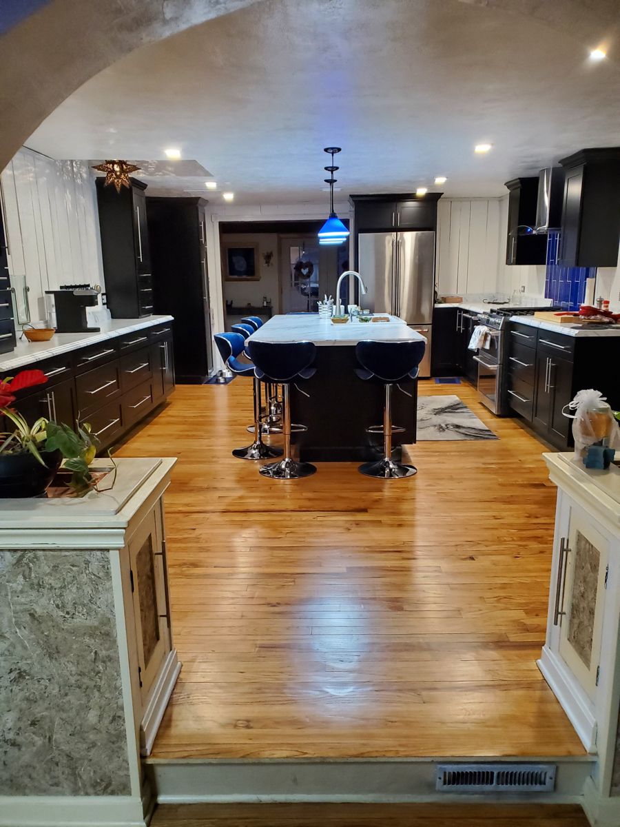 Black shaker kitchen cabinets with white countertops, blue lighting, and blue subway tile backsplash Black shaker kitchen cabinets with white countertops, blue lighting, and blue subway tile backsplash