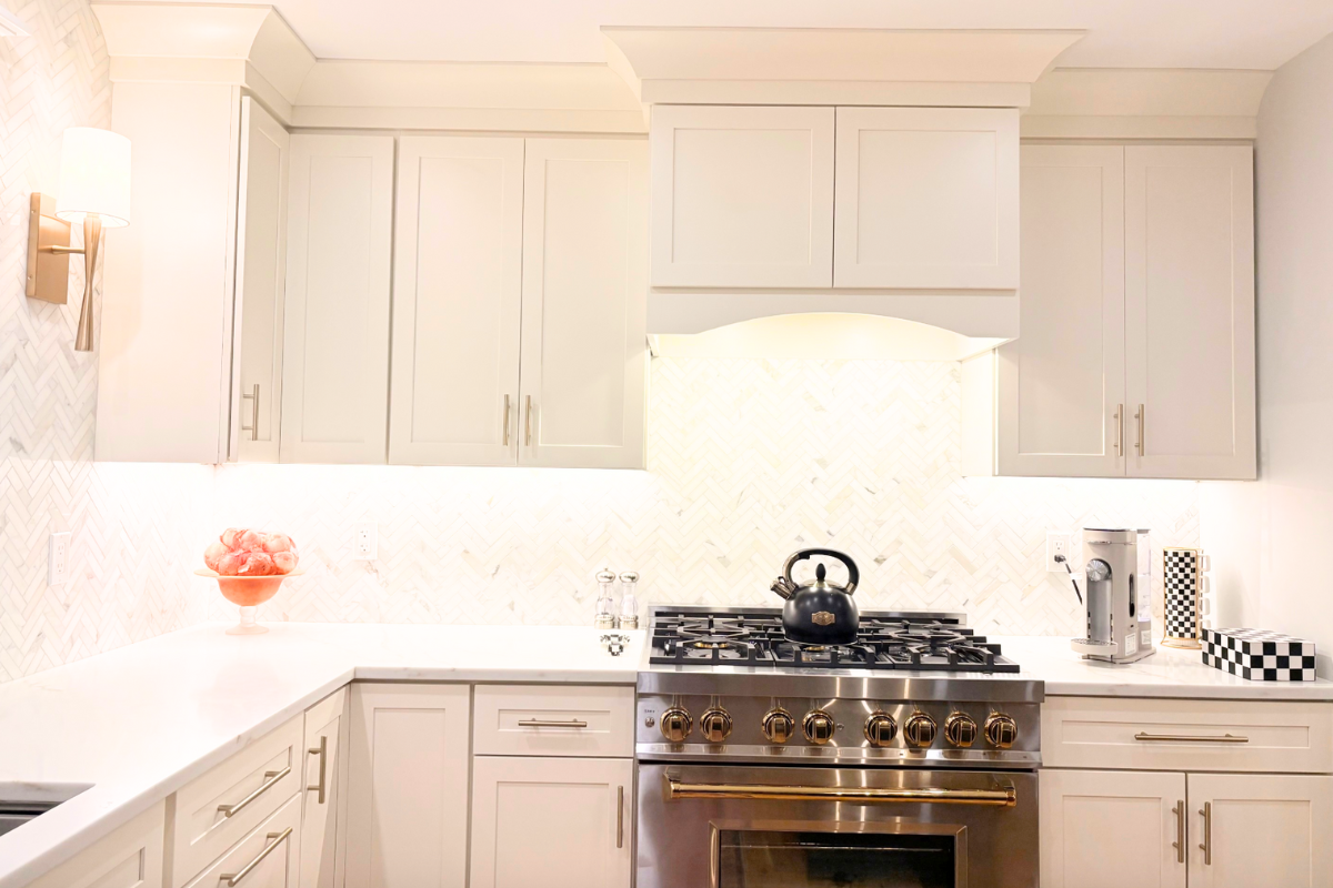 Large L-shaped white shaker kitchen design with a long navy island and white stone countertops