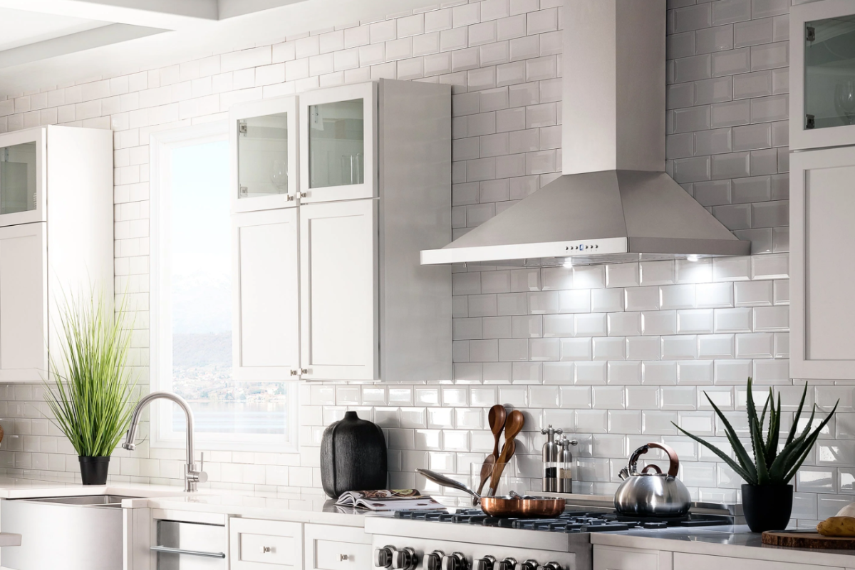 Angled stainless steel chimney hood between white stacked shaker kitchen cabinets Angled stainless steel chimney hood between white stacked shaker kitchen cabinets