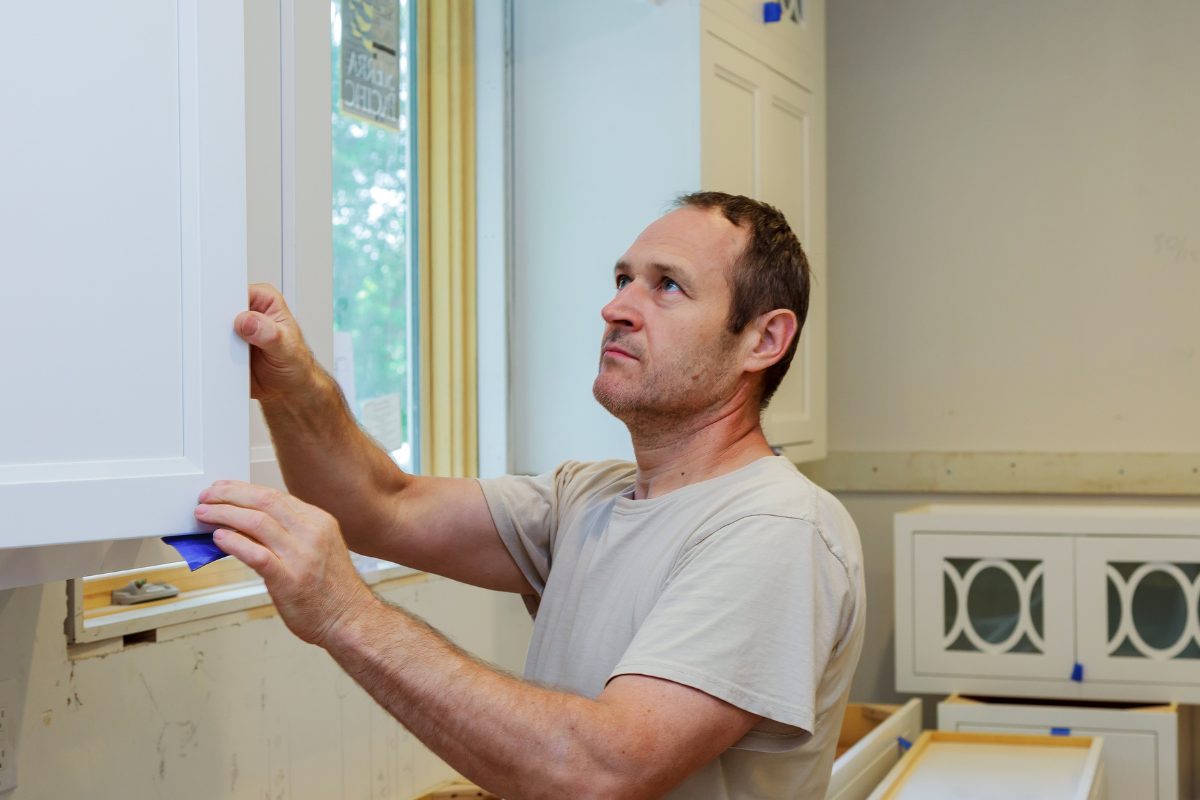Contractor installing white wall cabinet doors Contractor installing white wall cabinet doors