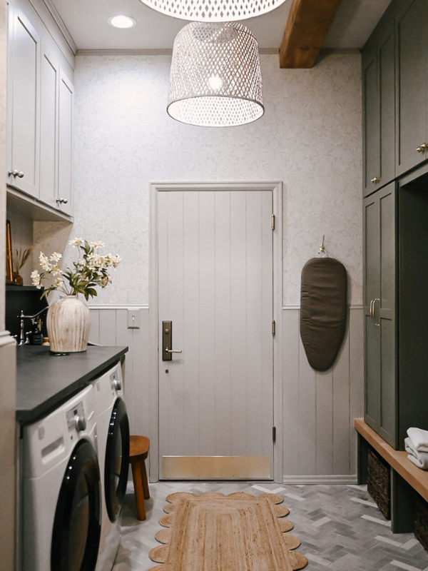Large laundry room with washer/dryer on left with taupe shaker cabinets above and decorative black countertop across with olive green mudroom lockers and white oak bench on the right Large laundry room with washer/dryer on left with taupe shaker cabinets above and decorative black countertop across with olive green mudroom lockers and white oak bench on the right
