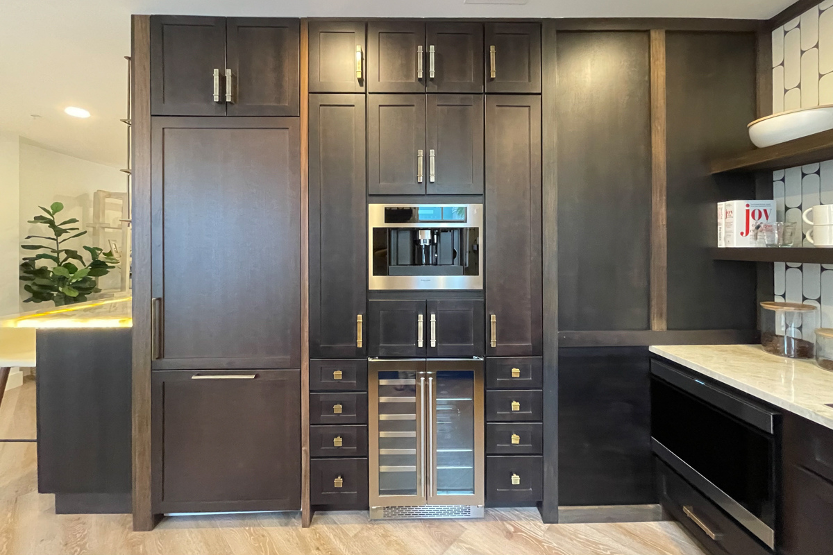 Small and chic U-shaped kitchen in dark brown shaker cabinets with wood floating shelves, white funky tile backsplash, and light brown quartz countertop with waterfall edge detail Small and chic U-shaped kitchen in dark brown shaker cabinets with wood floating shelves, white funky tile backsplash, and light brown quartz countertop with waterfall edge detail