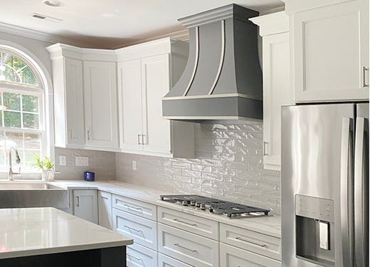 Dark gray wood range hood with steel strapping against white shaker kitchen cabinets Dark gray wood range hood with steel strapping against white shaker kitchen cabinets