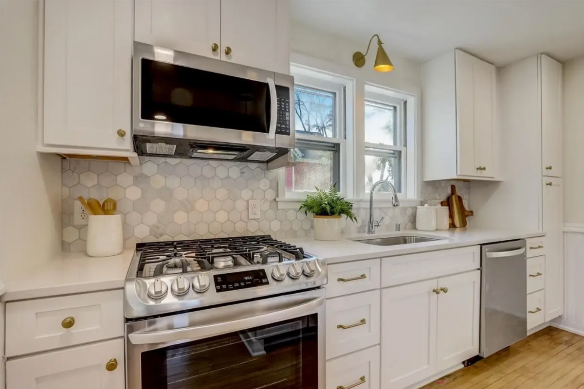 White shaker one-wall kitchen design with gold cabinet hardware and accents White shaker one-wall kitchen design with gold cabinet hardware and accents