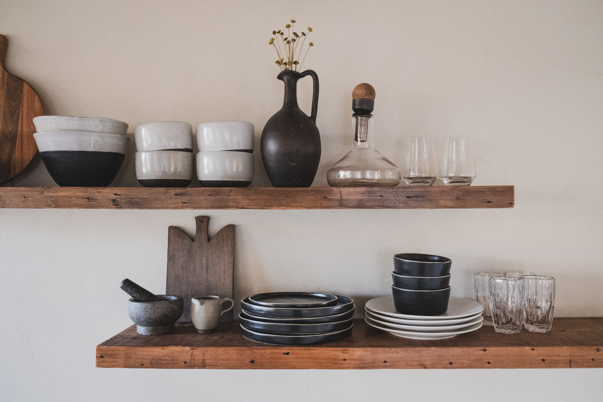 Decorative wood floating shelves holding stacked bowls and cups Decorative wood floating shelves holding stacked bowls and cups