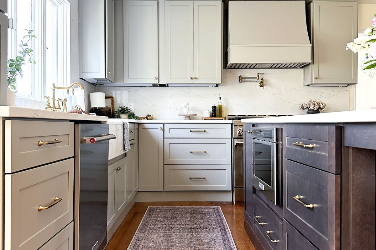 Light gray shaker kitchen with wood hood, white quartz countertops, and a large dark brown furniture-style island Light gray shaker kitchen with wood hood, white quartz countertops, and a large dark brown furniture-style island