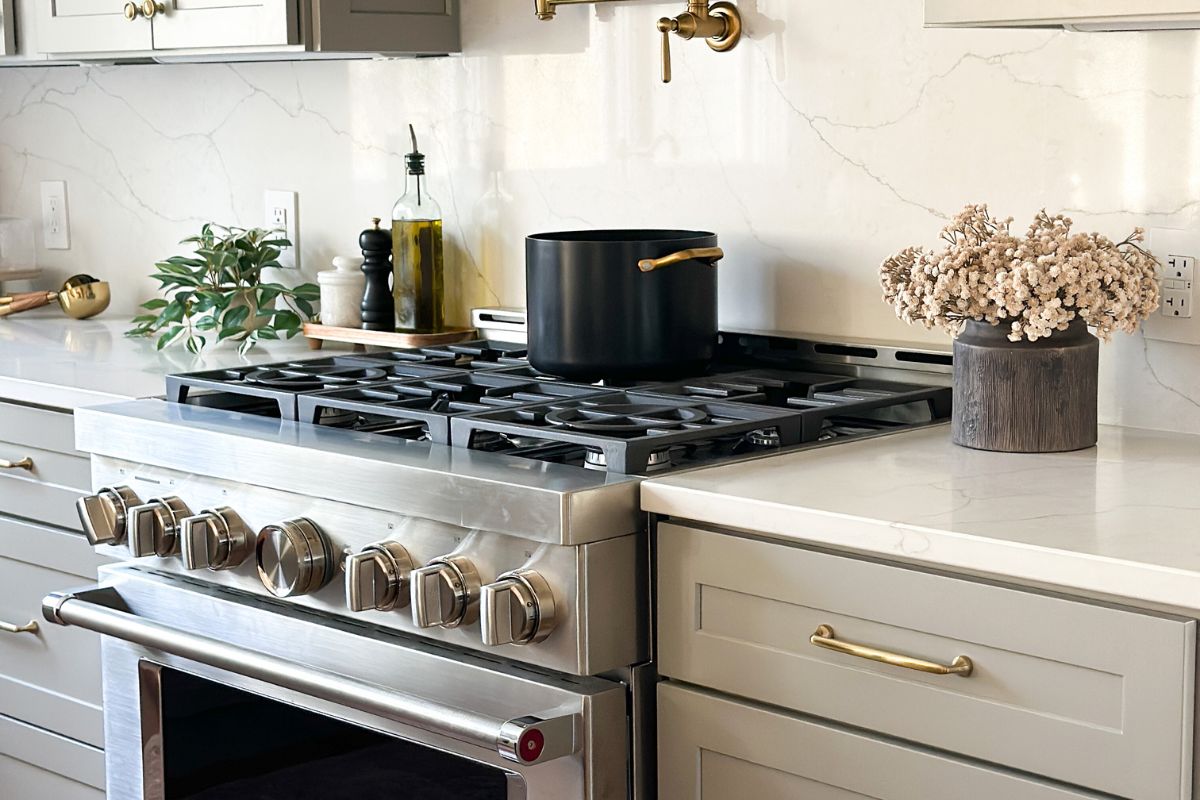 Light gray shaker kitchen cabinets with a large KitchenAid gas range and white quartz countertops Light gray shaker kitchen cabinets with a large KitchenAid gas range and white quartz countertops