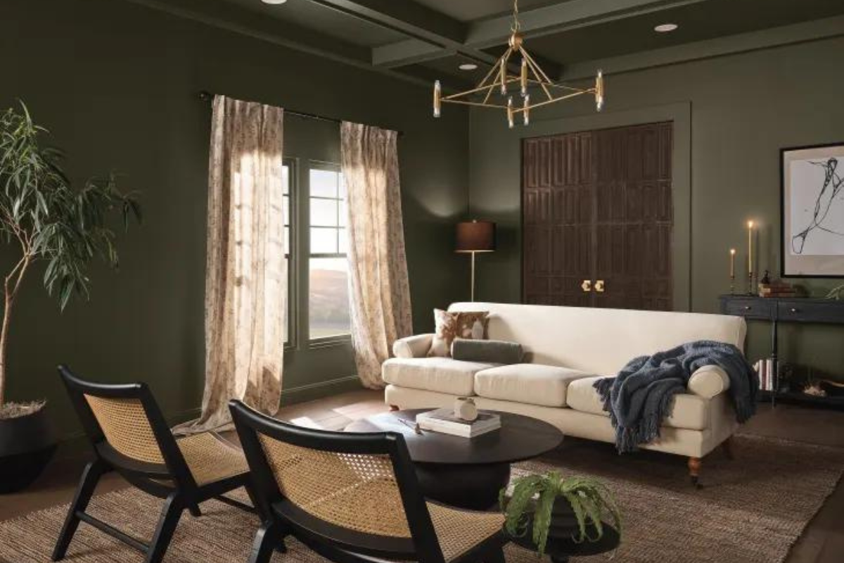 Moody living room with dark olive green wall paint and furniture with cream and tan finishes Moody living room with dark olive green wall paint and furniture with cream and tan finishes