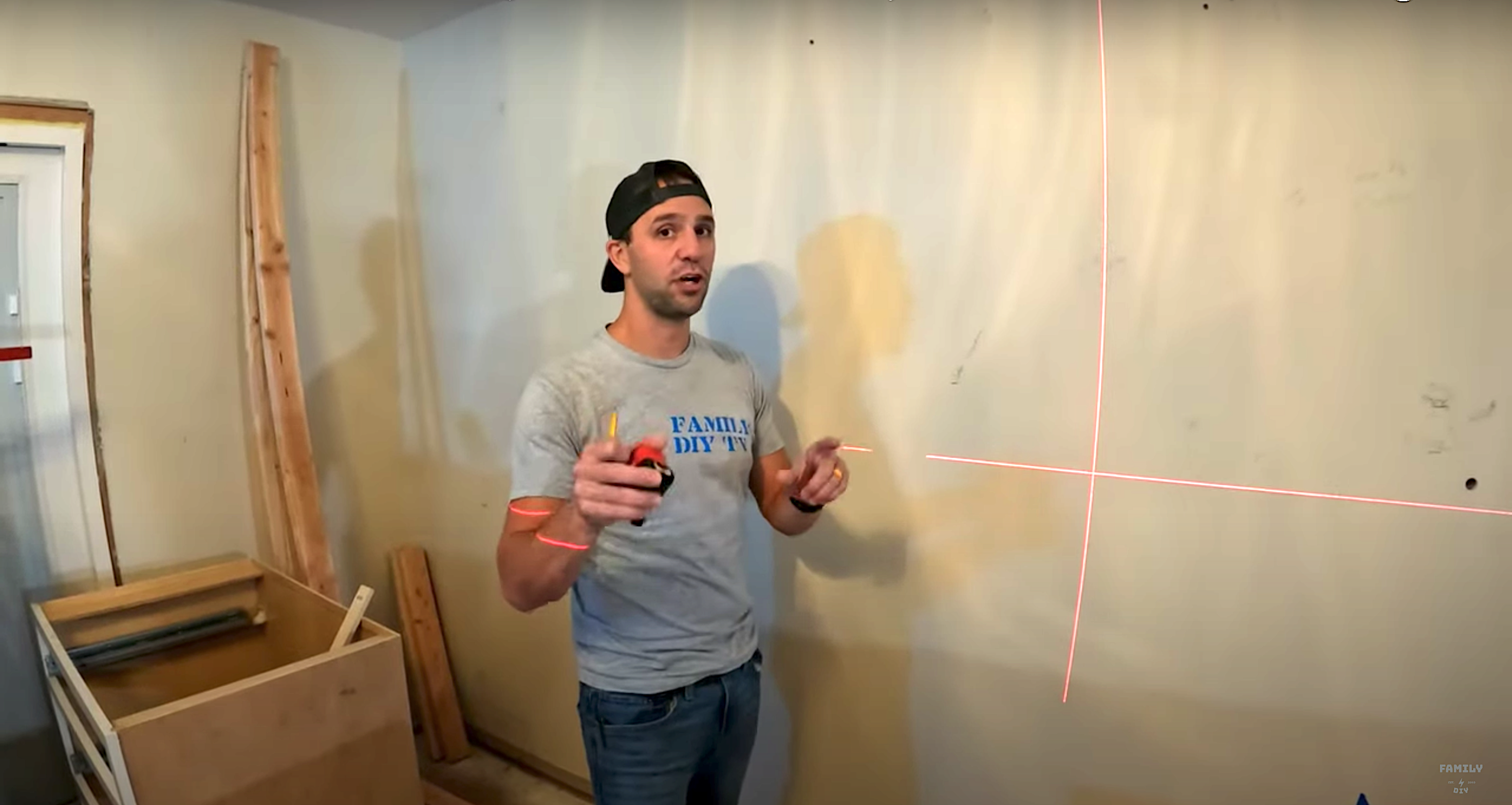 Mike Sante of Family DIY TV using a laser level on his wall before kitchen cabinet installation Mike Sante of Family DIY TV using a laser level on his wall before kitchen cabinet installation