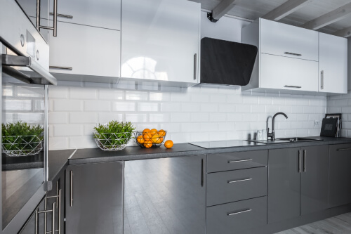 High-gloss kitchen cabinet design with white wall cabinets and gray base cabinets, dark gray countertops and a white subway tile backsplash High-gloss kitchen cabinet design with white wall cabinets and gray base cabinets, dark gray countertops and a white subway tile backsplash