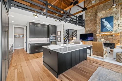 Harrison Carriage Black kitchen cabinets Large black shaker kitchen with stacked cabinets, double-sided island with seating and white marble quartz countertops.