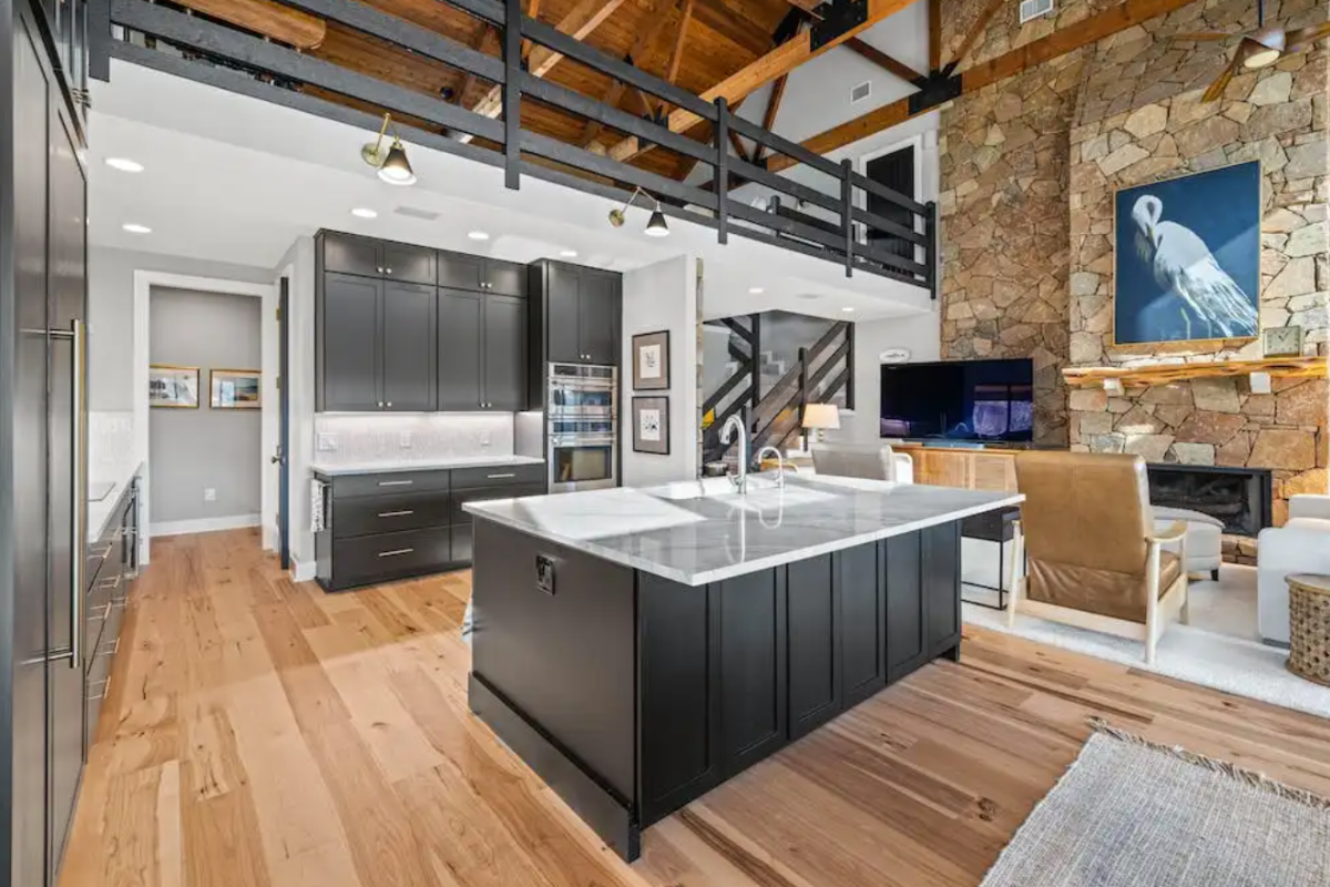 Large black kitchen design with stacked cabinets, white quartz countertops and rustic surroundings Large black kitchen design with stacked cabinets, white quartz countertops and rustic surroundings