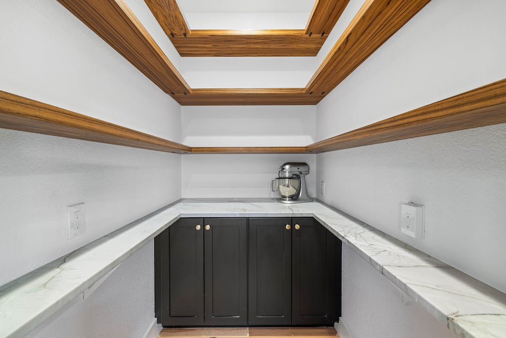 CliqStudios project: Black shaker pantry cabinets with a white wrap-around stone countertops and rustic floating shelves above CliqStudios project: Black shaker pantry cabinets with a white wrap-around stone countertops and rustic floating shelves above