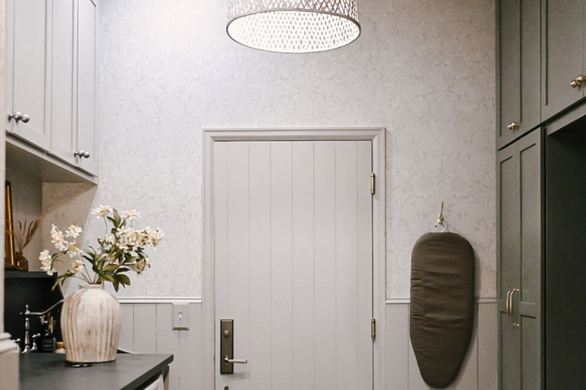 Large laundry room with washer/dryer on left with taupe shaker cabinets above and decorative black countertop across with olive green mudroom lockers and white oak bench on the right Large laundry room with washer/dryer on left with taupe shaker cabinets above and decorative black countertop across with olive green mudroom lockers and white oak bench on the right