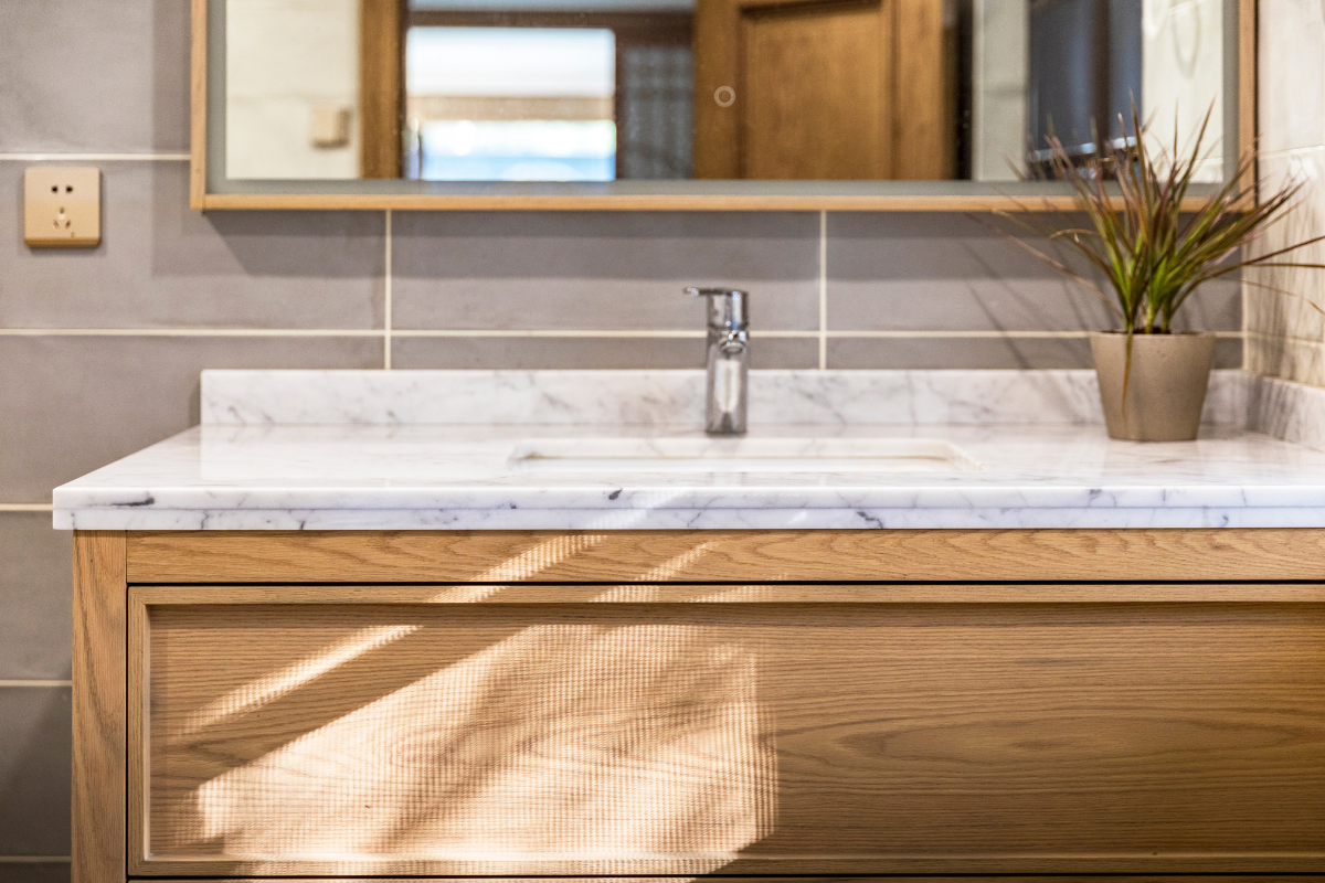 Close-up of an inset wood vanity cabinet with a thin marble countertop Close-up of an inset wood vanity cabinet with a thin marble countertop