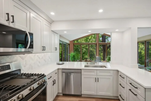Light gray shaker-style kitchen with U-shaped peninsula design Light gray shaker-style kitchen with U-shaped peninsula design and black cabinet hardware