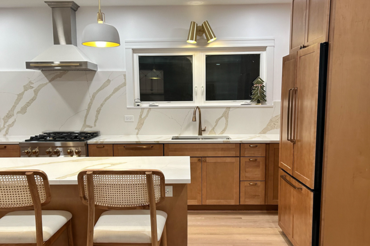 Upscale medium wood kitchen cabinets in shaker style with matching quartz countertops and slab backsplash Upscale medium wood kitchen cabinets in shaker style with matching quartz countertops and slab backsplash