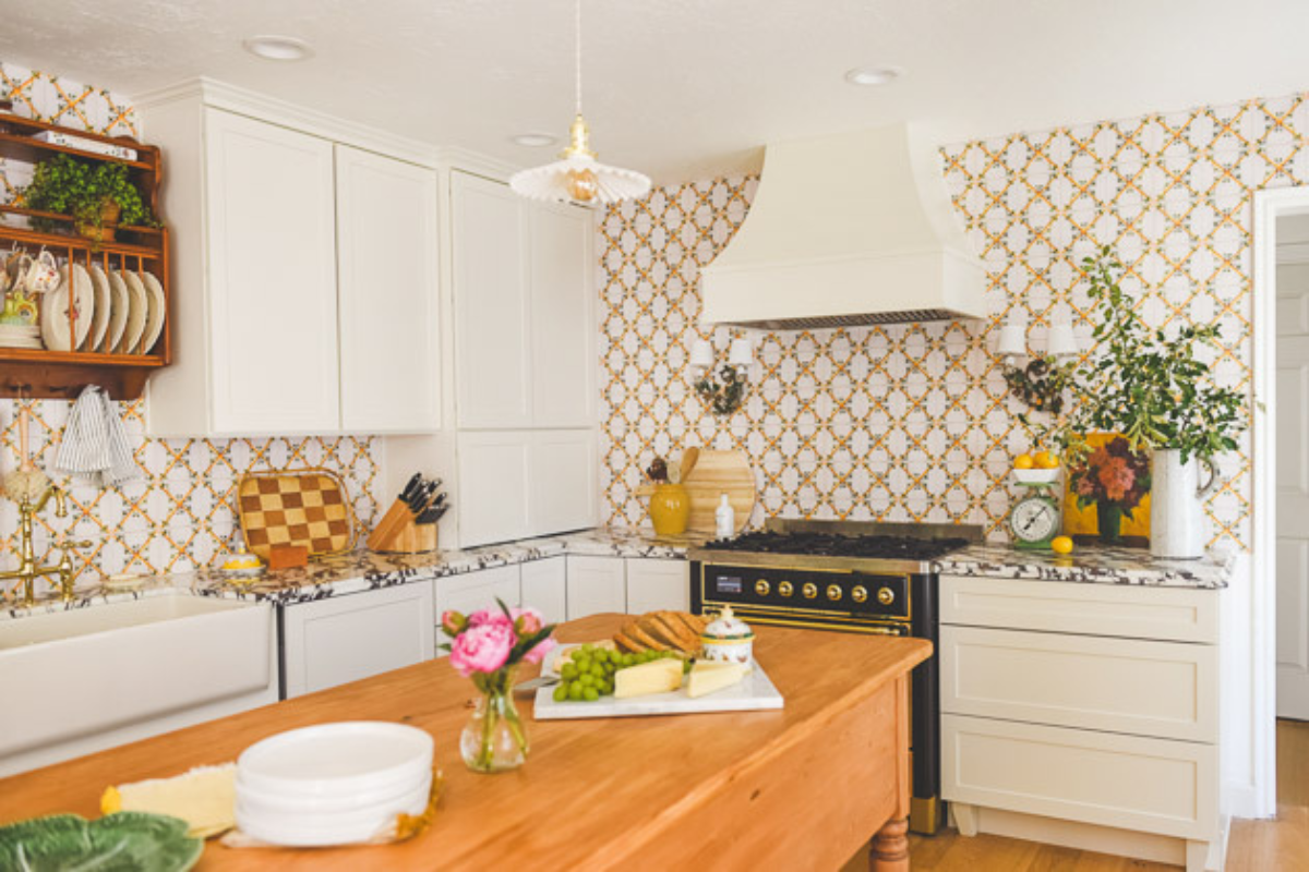 L-shaped cream shaker kitchen cabinet design with swedish influences, a matching wood kitchen hood, and vibrant orange and white tile backsplash L-shaped cream shaker kitchen cabinet design with swedish influences, a matching wood kitchen hood, and vibrant orange and white tile backsplash