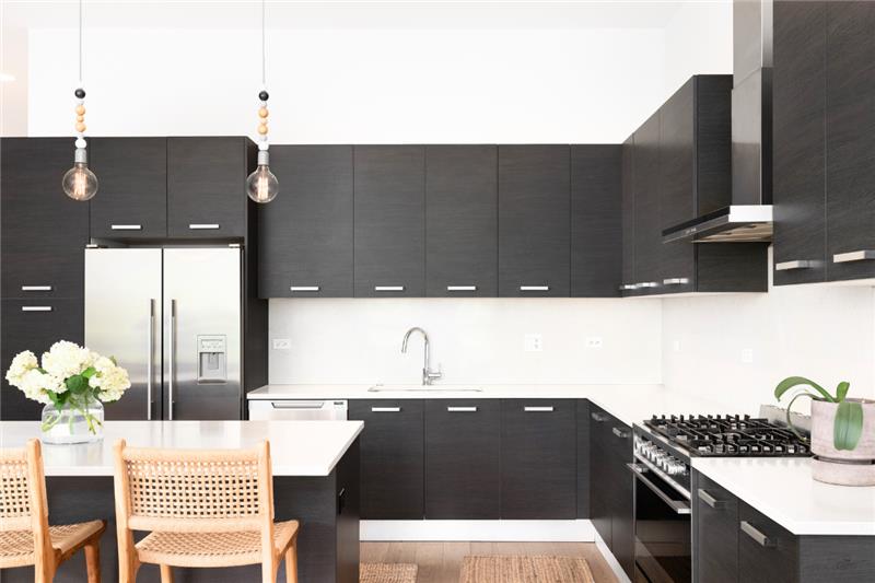 Pros & Cons of Matte Kitchen Cabinets L-shaped kitchen and island with matte black kitchen cabinets and white quartz countertops