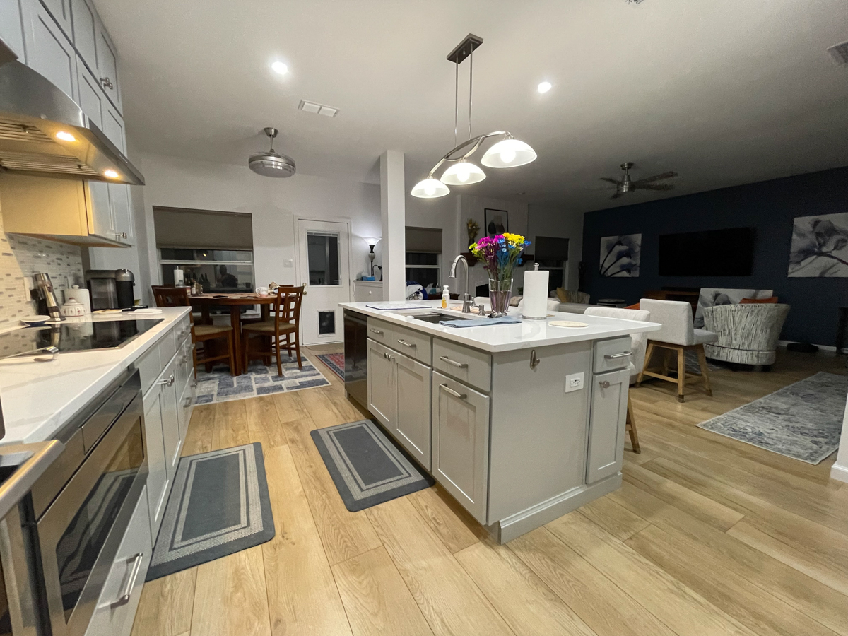 Light gray stacked shaker kitchen cabinets and island with white quartz countertops, brushed nickel cabinet hardware and modern pendant lighting Light gray stacked shaker kitchen cabinets and island with white quartz countertops, brushed nickel cabinet hardware and modern pendant lighting