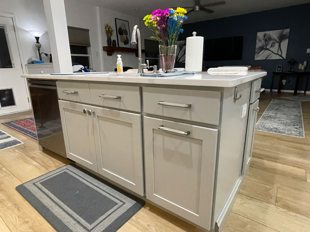 Light gray stacked shaker kitchen cabinets and island with white quartz countertops, brushed nickel cabinet hardware and modern pendant lighting Light gray stacked shaker kitchen cabinets and island with white quartz countertops, brushed nickel cabinet hardware and modern pendant lighting