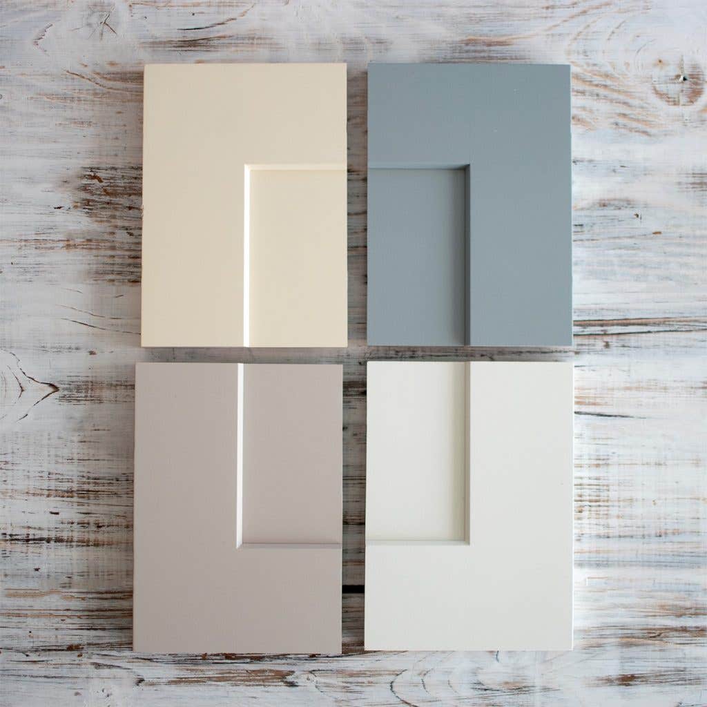 Four shaker cabinet door samples in cream, blue-gray, light gray, and white Four shaker cabinet door samples in cream, blue-gray, light gray, and white