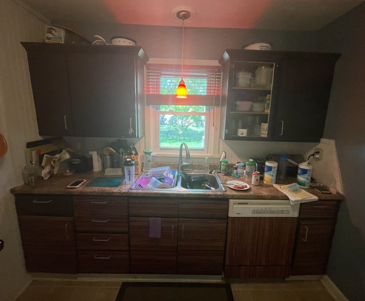 Over-crowded galley kitchen in dark and dingy finishes cluttered with household items Over-crowded galley kitchen in dark and dingy finishes cluttered with household items