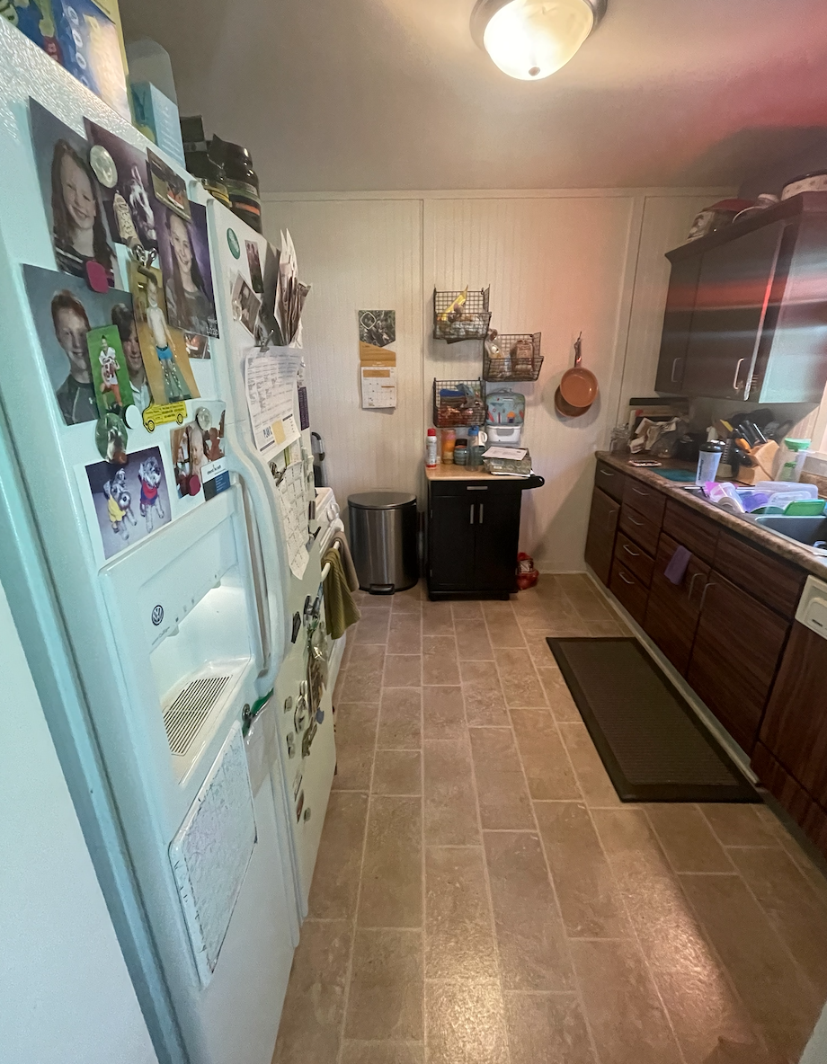 Over-crowded galley kitchen in dark and dingy finishes cluttered with household items Over-crowded galley kitchen in dark and dingy finishes cluttered with household items