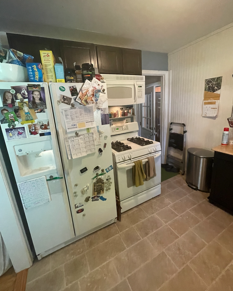 Over-crowded galley kitchen in dark and dingy finishes cluttered with household items Over-crowded galley kitchen in dark and dingy finishes cluttered with household items